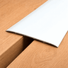 Extra wide 80mm self-adhesive aluminium floor transition strip installed between same-level laminate flooring